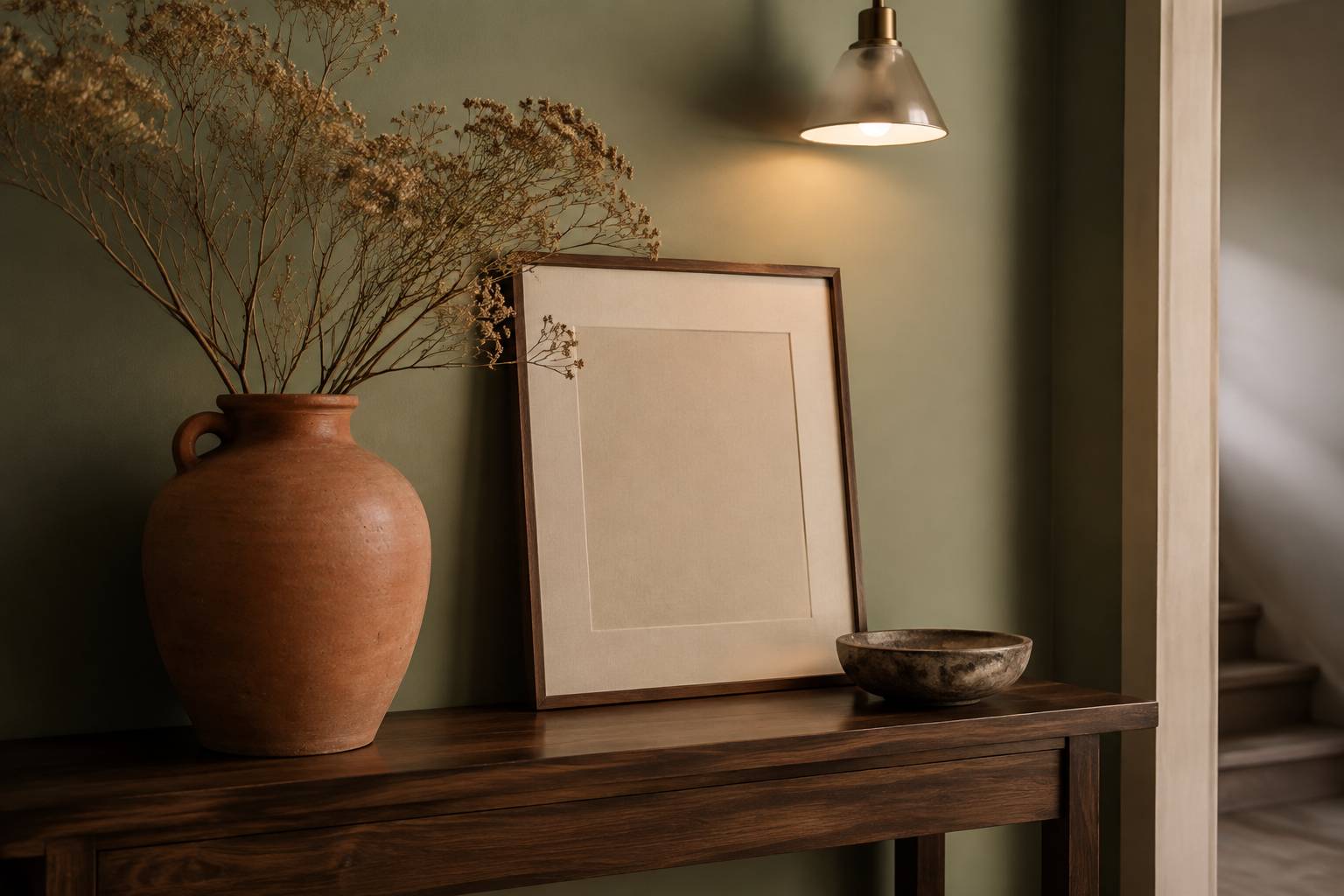 Console de couloir avec vase terracotta, branches séchées et suspension lumineuse